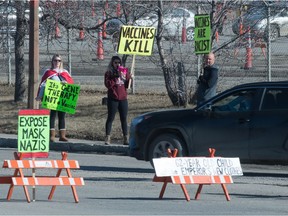 Demonstrators stand outside the entrance to the COVID-19 testing/vaccination facilities at Evraz Place in Regina, Saskatchewan on Mar. 17, 2021.