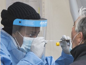 A medical worker prepares to take a swab from a patient at a clinic for COVID-19 testing in Montreal North.