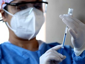 A nurse prepares a dose of the Pfizer-BioNTech vaccine against COVID-19. Pfizer and Moderna recommend that their two doses be given around 21 days apart, but Health Canada and the National Advisory Council on Immunization have agreed to stretch it out to 105 days.