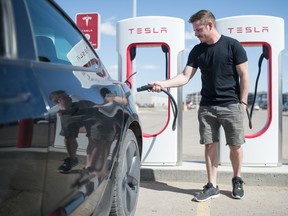 Joel Murray demonstrates how he would plug in his Telsa electric car at the electric car charging station in the parking lot of the Canadian Tire store on Prince of Wales Drive in Regina, Saskatchewan on April 7, 2021.