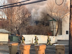 Firefighters walk around the back of a burning home on the 2700 block of Victoria Avenue in Regina, Saskatchewan on April 20, 2021.