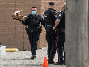 A police officers carries a destroyed suitcase following the deployment of an Explosives Disposal Unit robot after receiving a report about a suspicious package on the 900 block of Victoria Avenue in Regina, Saskatchewan on April 26, 2021.