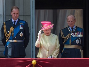 Britain's Queen Elizabeth II (2nd L) waves as she stands alongside Prince Philip, Duke of Edinburgh (2nd R), and Prince William, Duke of Cambridge following a flypast to mark the 75th anniversary of the Battle of Britain in London, on July 10, 2015.