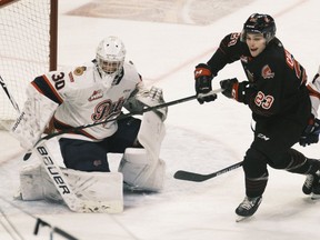 Regina Pats goalie Matthew Kieper keeps his eye on the puck while Atley Calvert (23) of the Moose Jaw Warriors prowls for a rebound in WHL action at the Brandt Centre on Monday.