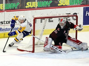 Saskatoon Blades' Brandon Lisowsky (right) attempts a wrap-around against Moose Jaw Warriors goaltender Boston Bilous on Friday night at the Brandt Centre.