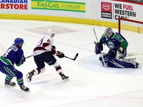 Regina Pats' Cole Carrier (21) shoots on Swift Current Broncos goalie Reid Dyck (30) while being chased by Chase Lacombe (4) at the Brandt Centre on April 22, 2021 at the Brandt Centre. Keith Hershmiller Photography.