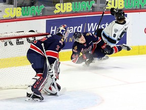 Regina Pats' Layton Feist (44) collides with Zachary Benson (9) of the Winnipeg Ice on April 12, 2021 at the Brandt Centre. Also shown is Pats goalie Roddy Ross. Keith Hershmiller Photography.