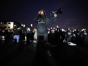 A person uses a megaphone as activists confront State troopers, National Guard members and other law enforcement officers following a march for Daunte Wright, 20, who was shot and killed by former Brooklyn Center Police Officer Kim Potter, in Brooklyn Center, Minnesota, April 13, 2021.