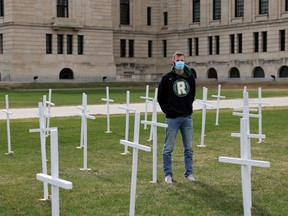 Ret Brailsford, left, spokesperson for Regina Harm Reduction Coalition, stands amongst the crosses on the front lawn of the legislative Building in Regina on Saturday, May 8, 2021. The crosses honour people who have died from drug overdoses and to call for more action on harm reduction from the provincial government.