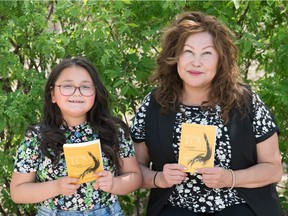 Bevann Fox, right, author of Genocidal Love: A Life After Residential School, sits with her granddaughter Chenia Fox, while holding copies of the book near the Saskatchewan Legislative Building in Regina, Saskatchewan on May 18, 2021. Chenia is the same age Bevann was when she was sent to residential school.