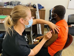 Dr. Jacelyn Hanson, a family physician with the Refugee Engagement and Community Health Clinic (REACH), administers a dose of COVID-19 vaccine to Abacar Mohamed at a vaccine clinic for newcomers to Canada held at the Global Gathering Place in Saskatoon on May 16, 2021.