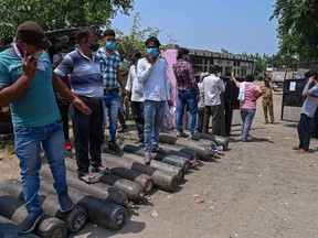 In this picture taken on May 5, 2021, people wait to refill their cylinders with medical oxygen for the Covid-19 coronavirus patients at Kalinga oxygen refilling centre in Moradabad.