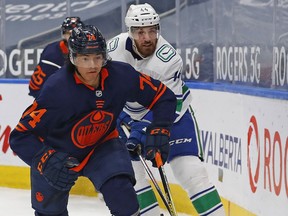 May 15, 2021; Edmonton, Alberta, CAN; Edmonton Oilers defensemen Ethan Bear (74) and Vancouver Canucks forward Tyler Graovac (44) chase a loose puck during the second period at Rogers Place. Mandatory Credit: Perry Nelson-USA TODAY Sports