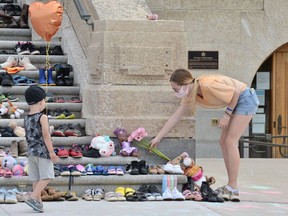 Flowers are placed on a display of children's shoes representing children who died while in Canada's residential school program on the steps of the Saskatchewan Legislative Building in Regina, Saskatchewan on May 31, 2021. BRANDON HARDER/ Regina Leader-Post