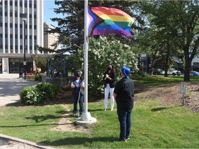 From left, Queen City Pride co-chair Lisa Phillipson, Regina Mayor Sandra Masters, and Queen City Pride co-chair Dan Shier are seen as the Pride flag is hoisted at City Hall in Regina on June 4, 2021. The flag was left at half mast to pay respect to the 215 children whose bodies were recently found buried on the property of a former residential school in British Columbia.
