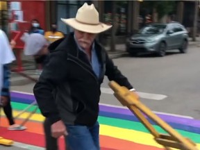 A man is seen walking away with part of a road barricade during an incident at Broadway Avenue and 10th Street on June 9, 2021. Screen grab from video/@terse_corvid