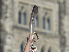 An eagle feather is held up during a rally for Missing and Murdered Indigenous Women and Girls on Parliament Hill in Ottawa, Tuesday Oct. 4, 2016.