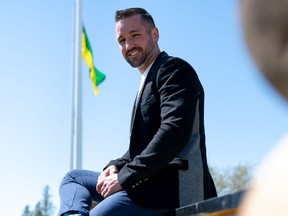 La Ronge Mayor Colin Ratushniak sits on the town's sign in May 2021. (Saskatoon StarPhoenix / Brandon White).