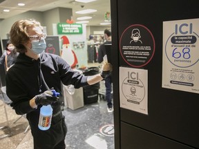 A clerk washes walls in front of signs that indicate the total number of customers allowed inside a store at the Complexe Desjardins shopping centre on Friday, December 4, 2020.