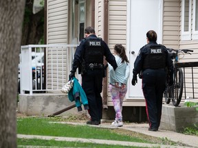 Police escort a person in custody from a residence on the 2300 block of Retallack Street in Regina, Saskatchewan on June 9, 2021.