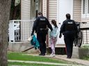 Police escort a person in custody from a residence at Block 2300 Retallack Street in Regina, Saskatchewan, June 9, 2021.