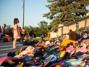 A young girl looks at a collection of children's backpacks on the steps of the Saskatchewan Legislative Building during a vigil event, pertaining to the Cowessess and Kamloops discoveries.