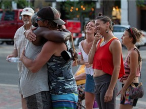 People hug during a jam session from Oral Fuentes Reggae Band in front of Victoria School on Broadway Avenue while a new normal sets in as COVID-19 health restrictions ease. Photo taken in Saskatoon on July 1, 2021.