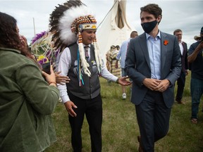 Cowessess First Nation Chief Cadmus Delorme, left, leads Prime Minister Justin Trudeau back to the speaking area during an event surrounding the signing of a document, marking the transfer of control of children in care to the First Nation, held on Cowessess on July 6, 2021.