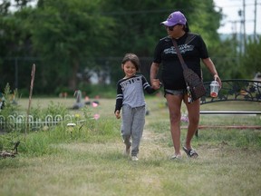 Rhiana Cote, right, leads daughter Sophia Nekrasoff away from Cote's son's marked grave at the site where hundreds of unmarked graves were found on Cowessess First Nation in Saskatchewan on July 8, 2021. The visit was the first the pair made to the site since the discovery of the unmarked graves. BRANDON HARDER/ Regina Leader-Post