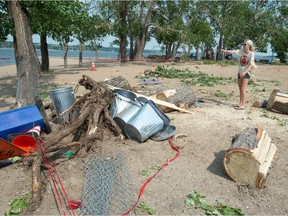 Sask Aquatic Adventures co-owner Steph Baer shows the area where the company's kayak and paddle board rental shed stood at Regina Beach on July 12, 2021. High winds from a summer storm pushed a tree over, which fell on and destroyed the shed. The tree's roots can be seen pulled up in the photo.