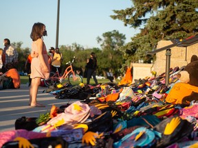 A young girl looks at a collection of children's backpacks on the steps of the Saskatchewan Legislative Building during a Canada Day vigil for the grave discoveries Cowessess and Kamloops.