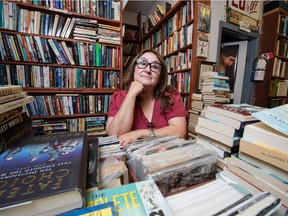 Christine Scott, co-owner of Centennial Books, sits at a desk surrounded by books at her store in Regina.