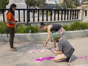 The Regina Downtown BID, Warehouse BID and the Regina Farmers' Market are hosting the collaborative Footprints Commemorative Indigenous Art Project, to commemorate the individuals found in unmarked graves on residential school sites in Saskatchewan. Indigenous artist Brandy Jones, left, looks on as José O'Blenis and her daughter Andy stencil her designs onto the sidewalk on Saturday, August 14, 2021 in Regina.