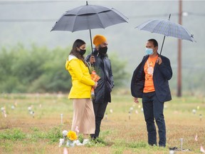 Federal NDP Leader Jagmeet Singh, centre, and his wife Gurkiran Kaur Sidhu, left, speak with with Cowessess First Nation Chief Cadmus Delorme at the site where hundreds of unmarked graves were discovered on Cowessess First Nation in Saskatchewan during a visit by Singh on August 20, 2021.