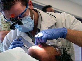 (REGINA, SASK - Mar. 5, 2012  - Mark Talbot (top) works on Mario Manaois's (bottom) teeth at Dental Day at the SIAST Dental Clinic campus in Regina.