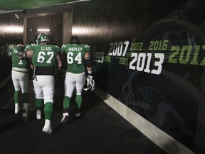 Saskatchewan Roughriders quarterback Cody Fajardo, 7, is comforted by teammates Dan Clark, 67, and Dakoda Shepley, 64, while walking to the dressing room after a heartbreaking loss to the visiting Winnipeg Blue Bombers in the CFL's 2019 West Division final.