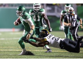 Saskatchewan Roughriders quarterback Cody Fajardo (7) tries to run past the tackle of Hamilton Tiger-Cats linebacker Simoni Lawrence (21) on Saturday, August 14, 2021 in Regina. TROY FLEECE / Regina Leader-Post