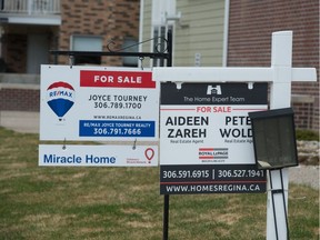 This file photo shows for sale signs posted on the lawn of a property on Angus Street in Regina, Saskatchewan on May 6, 2020. A recent report states the housing market in Saskatchewan is "cooling."