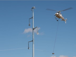 A helicopter strings rope between large power line structures on the north end of Regina, Saskatchewan on Sept. 2, 2021.