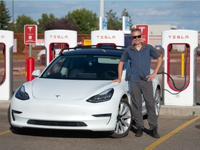 Jeff Moore stands next to his Tesla automobile at the charging station on Prince of Wales Drive in Regina, Saskatchewan on Sept. 14, 2021.