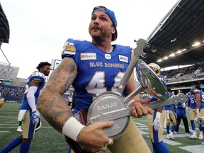 Winnipeg Blue Bombers long-snapper Mike Benson celebrates with the Banjo Bowl trophy after Saturday's 33-9 victory over the Saskatchewan Roughriders.