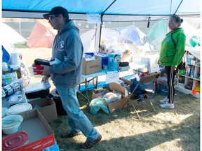 Volunteers are seen inside a supply tent at Camp Marjorie, a tent encampment for homeless people, in Pepsi Park in Regina, Saskatchewan on Oct. 18, 2021. On frame left is Shylo Stevenson, holding Naloxone which is a drug to combat opioid overdose.