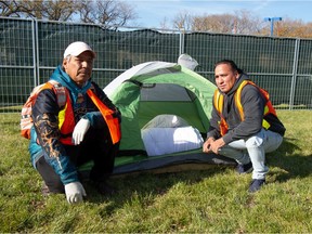 Volunteers Randy Netmaker, left, and Wallace Mckay kneel for a photo after outfitting a tent with bedding at Camp Marjorie, a tent encampment for homeless people, in Pepsi Park in Regina, Saskatchewan on Oct. 18, 2021.