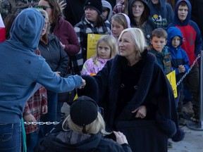 Independent MLA Nadine Wilson shakes hands with people in a large crowd in front of the Saskatchewan Legislative Building at a gathering against public health measures in October.