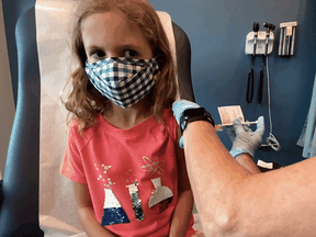 A seven-year-old girl is inoculated with a reduced dose of the Pfizer-BioNTech COVID-19 vaccine during a trial at Duke University in Durham, N.C., on Sept. 28, 2021.
