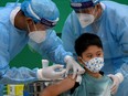 FILE: The grandson of Cambodia's Prime Minister Hun Sen receives a dose of the Sinovac Covid-19 coronavirus vaccine at the Peace Palace in Phnom Penh on September 17, 2021, as the country begins vaccinating children aged between six and 12.