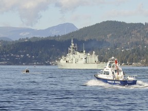 A file photo shows HMCS Calgary, top, as it is escorted out to sea in the waters near Vancouver's Stanley Park in February 2009.