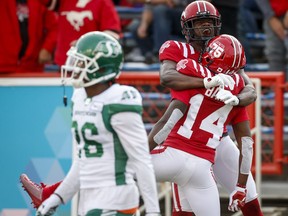 Saskatchewan Roughriders linebacker Godfrey Onyeka, left, walks away as the Calgary Stampeders' Shawn Bane, right, celebrates his touchdown with teammate Hergy Mayala on Oct. 2 at McMahon Stadium. The Roughriders allowed two early touchdowns during a 23-17 loss in Calgary.