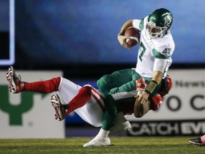 Saskatchewan Roughriders quarterback Cody Fajardo, right, is sacked by Calgary Stampeders' Folarin Orimolade during first half CFL football action in Calgary.