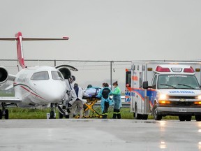 Medical personnel transfer a patient from an air ambulance which departed Regina to a waiting ambulance at Pearson International Airport in Mississauga on Oct 25, 2021.